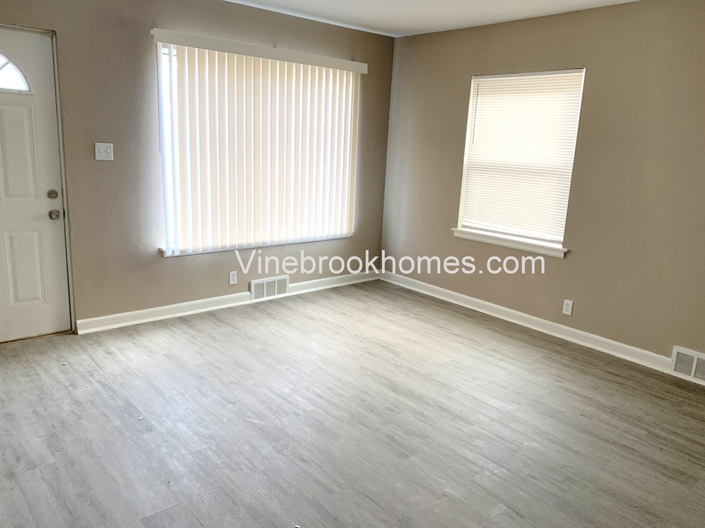 a small living room with a door and two windows