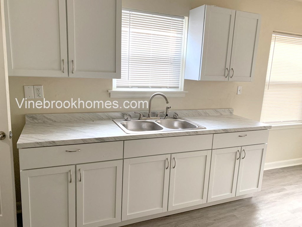 a white kitchen with white cabinets and a sink