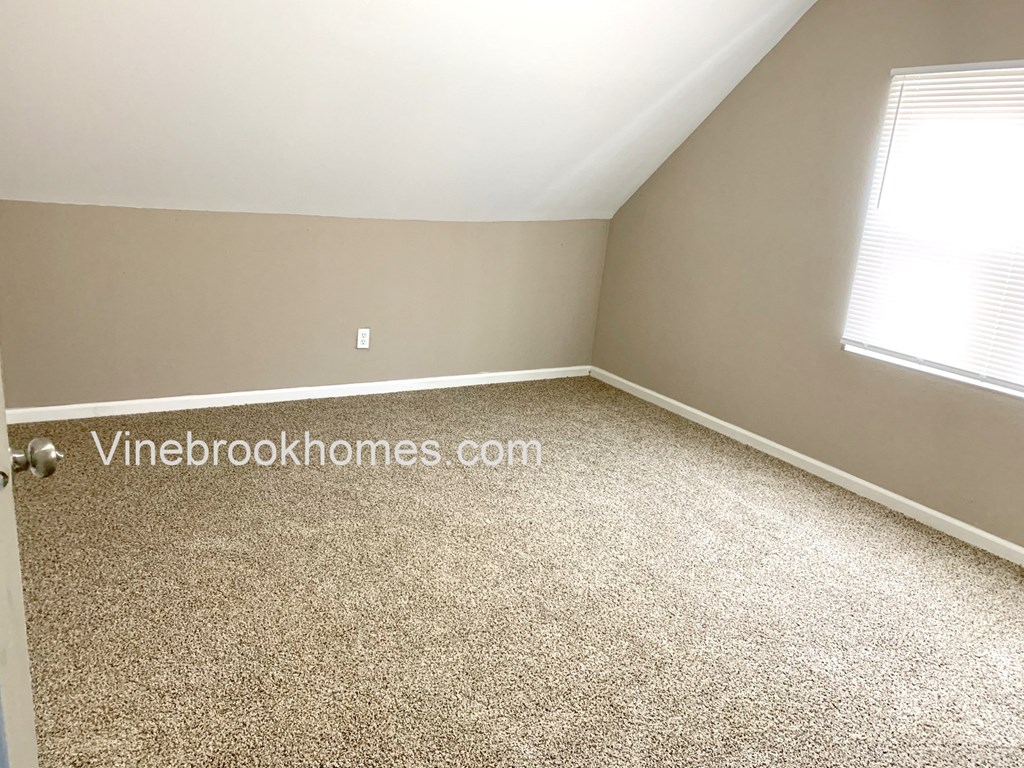 a small bedroom with carpet and a window