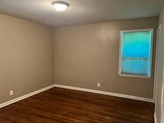 a empty bedroom with a window and a wooden floor
