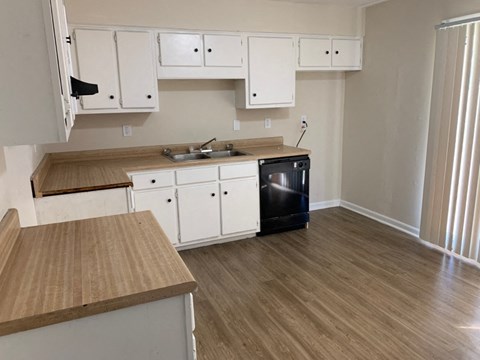 A kitchen with white cabinets and a wooden countertop.