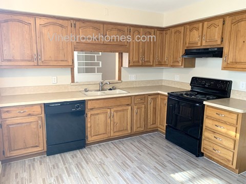 A kitchen with wooden cabinets and black appliances.
