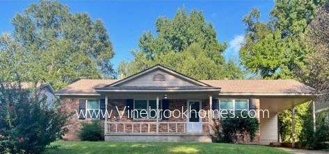 a house with a porch and trees in the background