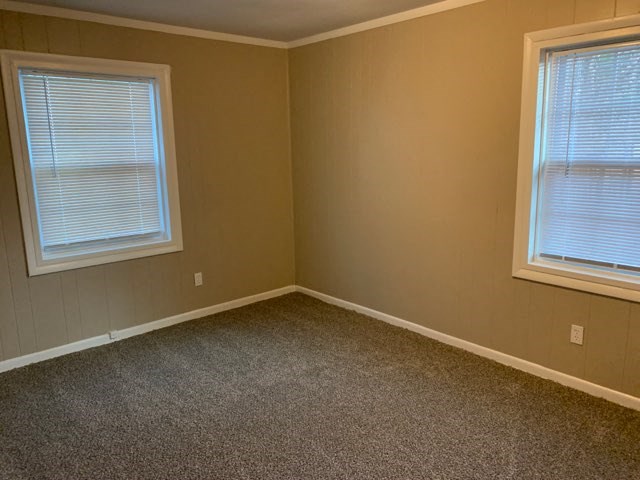 an empty room with two windows and a carpet
