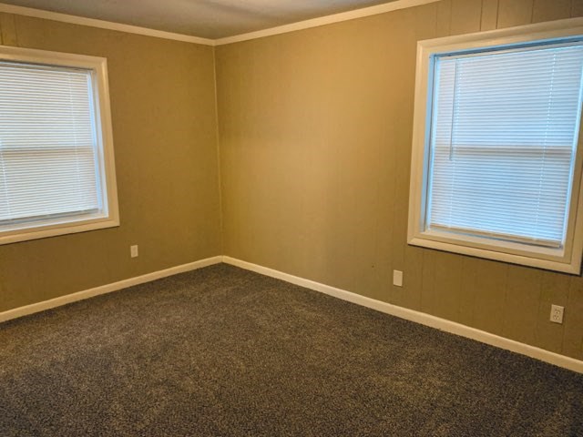 an empty room with two windows and a carpet