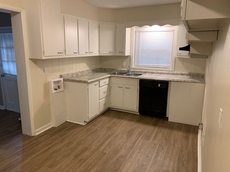an empty kitchen with white cabinets and a sink