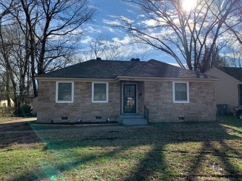 a small brick house with a lawn and trees