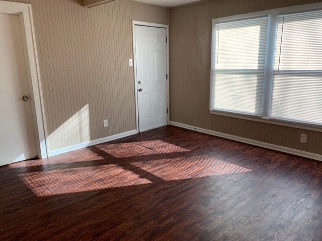 an empty living room with wood floors and a door