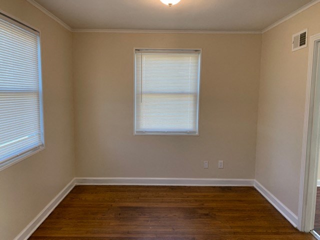 a empty room with a wooden floor and two windows