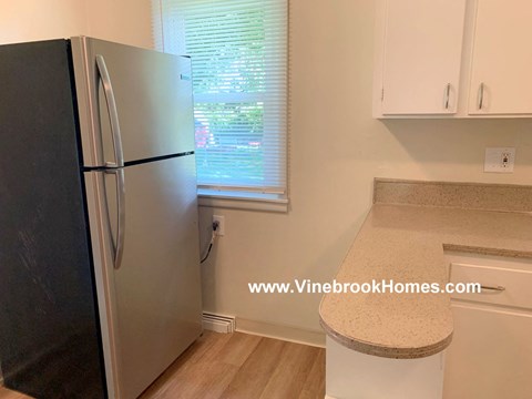A black refrigerator is in a kitchen with a countertop and cabinets.