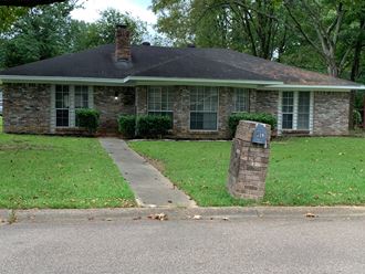 a small brick house with a stone pillar in the front