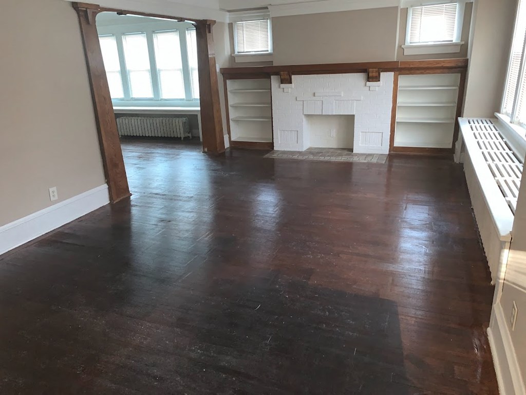 an empty living room with wood floors and a fireplace