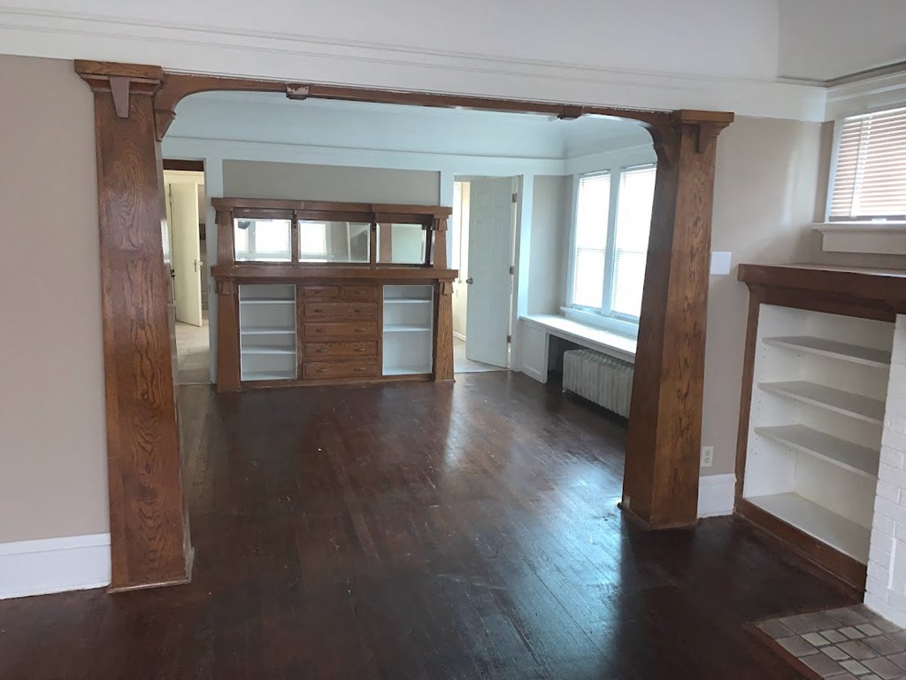 a living room with a hard wood floor and wood columns