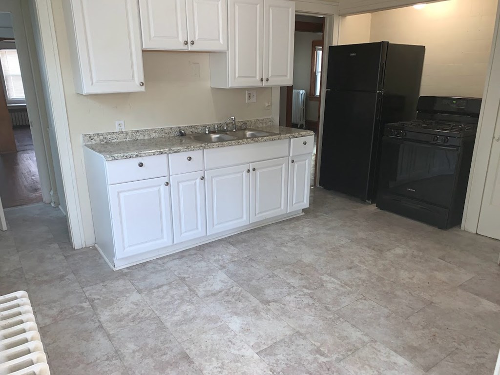 a kitchen with white cabinets and a black refrigerator