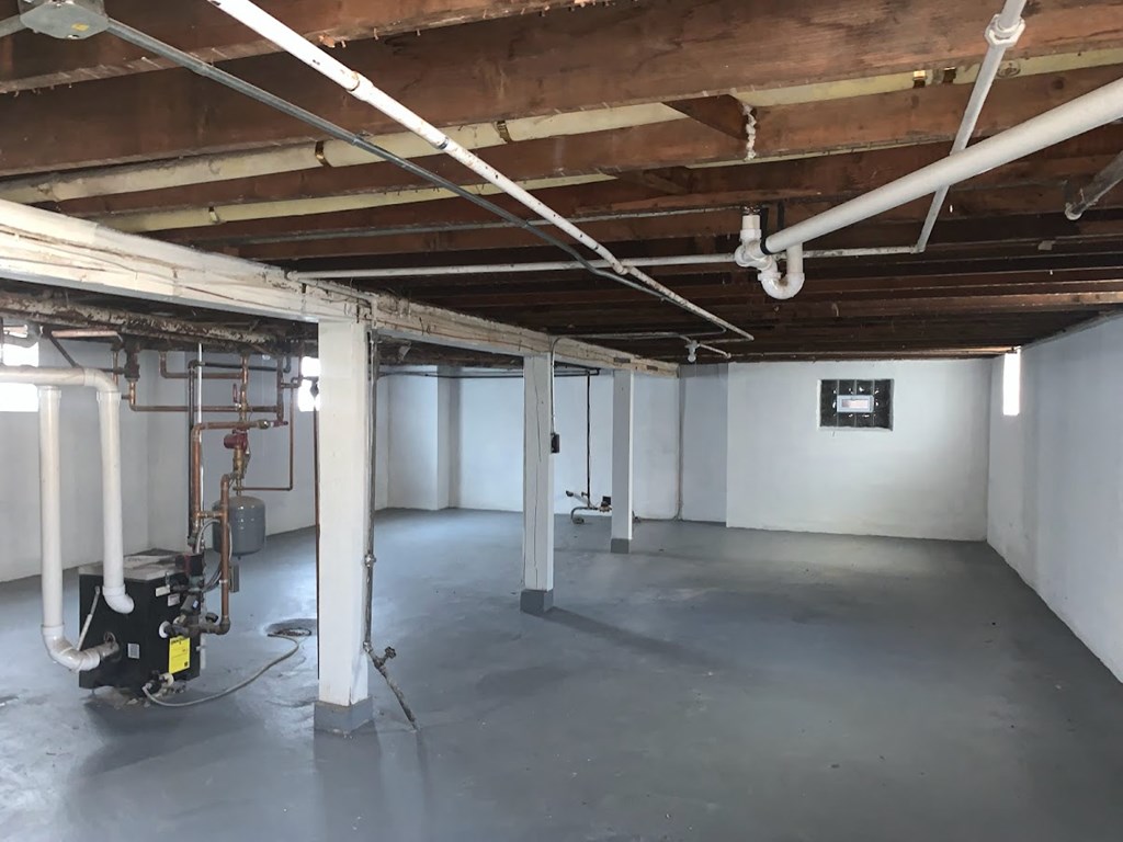 the inside of a building with white walls and exposed pipes