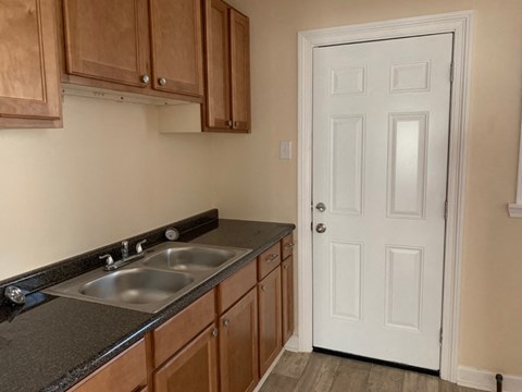 A white door is in a kitchen with brown cabinets.