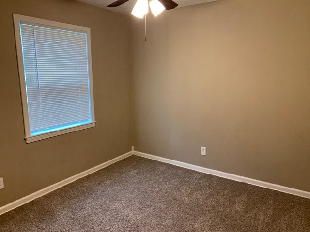an empty room with a window and a ceiling fan