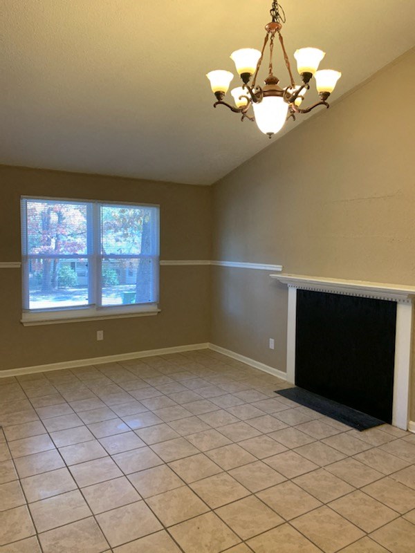 an empty living room with a fireplace and tiled floor