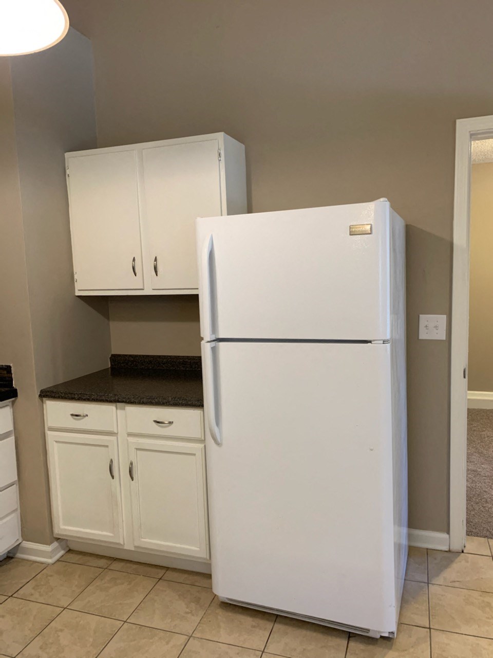 a white refrigerator in a kitchen with white cabinets