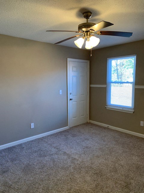 an empty room with a ceiling fan and a door