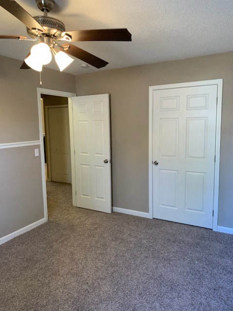 an empty bedroom with a ceiling fan and a door