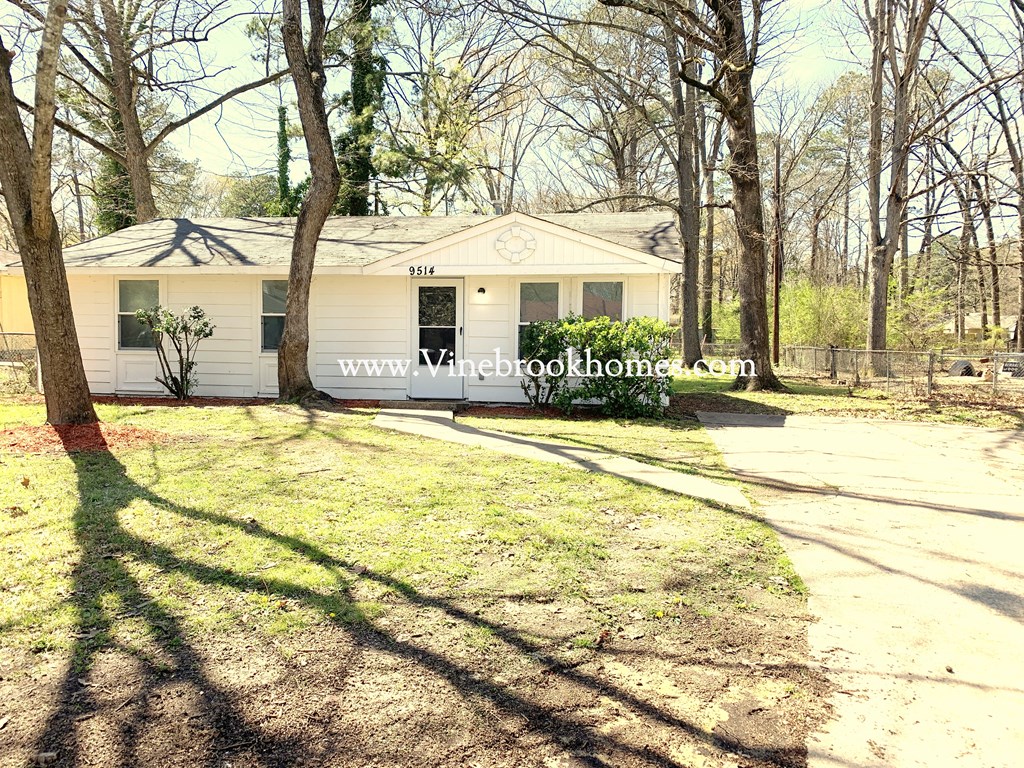 a small white house with a yard and trees