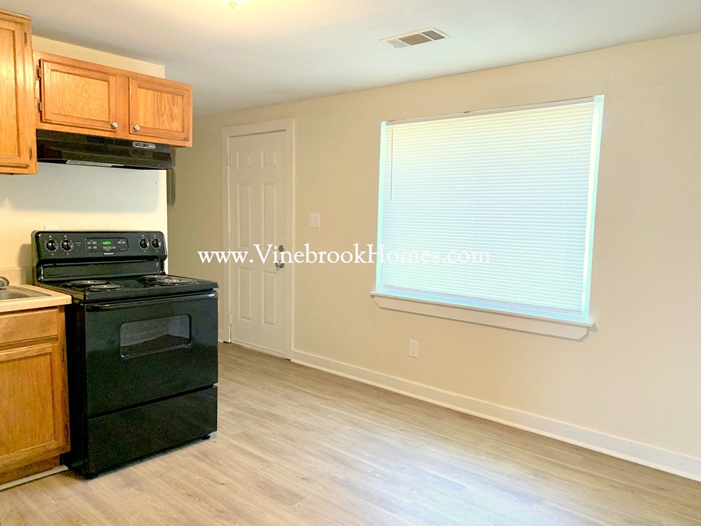 a kitchen with black appliances and wooden cabinets and a window