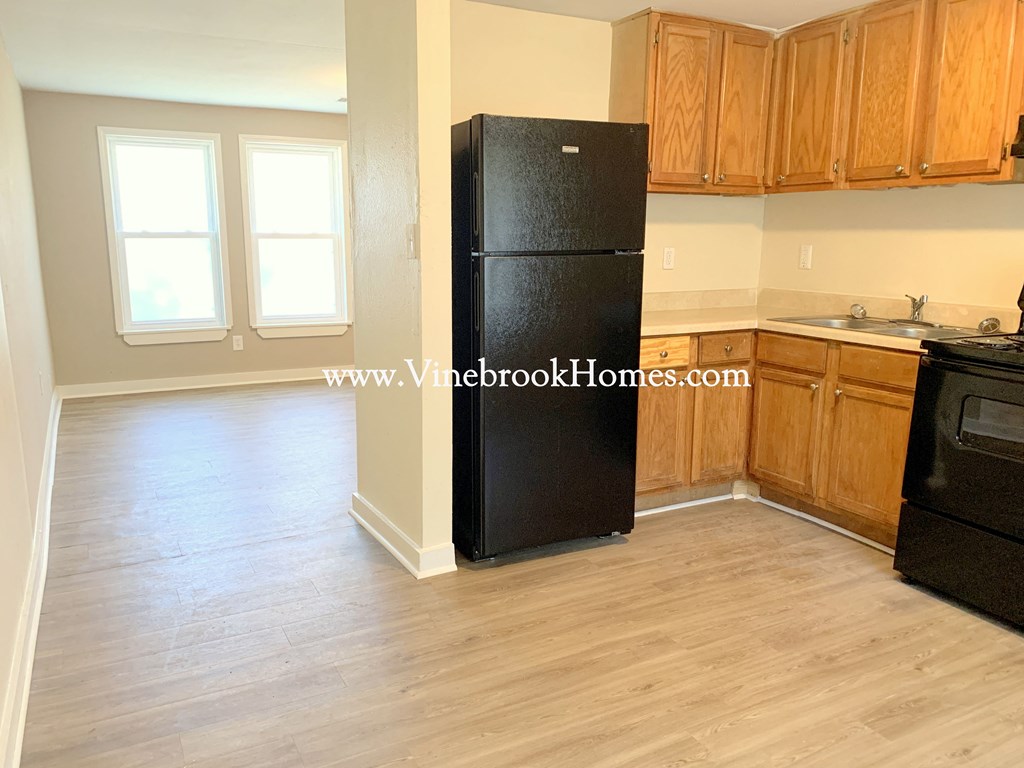 a kitchen with black refrigerator and wooden cabinets