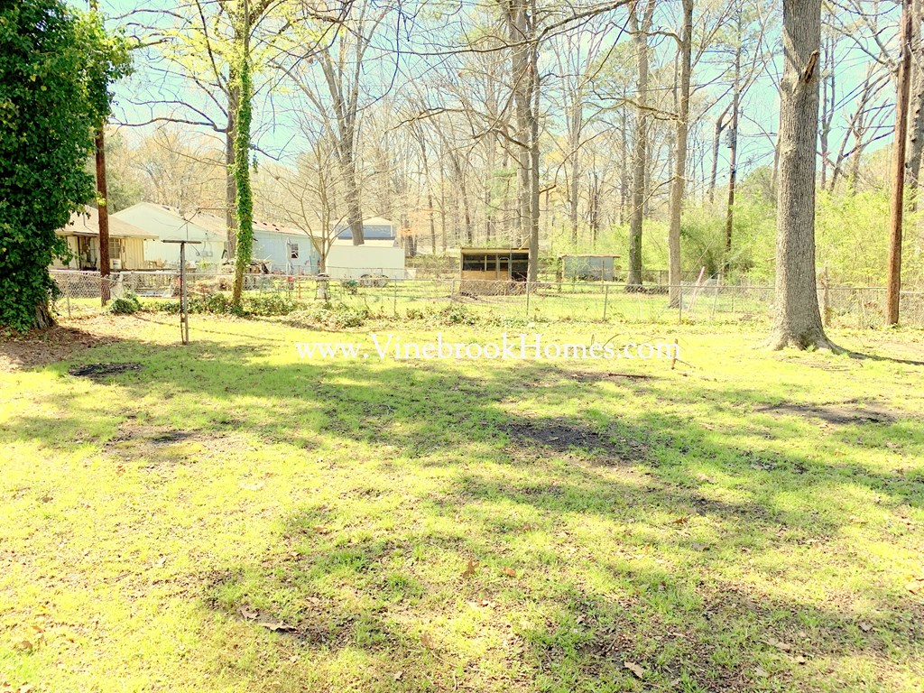 the backyard of the house has a large yard and trees
