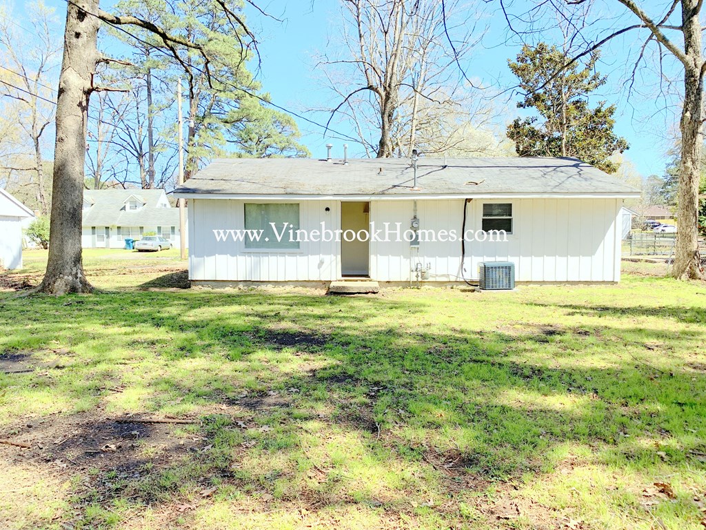 the front of a small white house with a lawn and trees