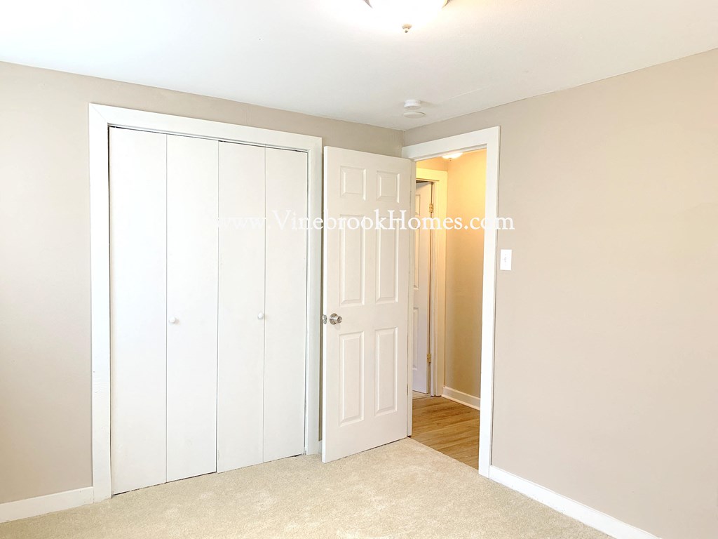 a bedroom door is open to a closet and a hallway with a door to a