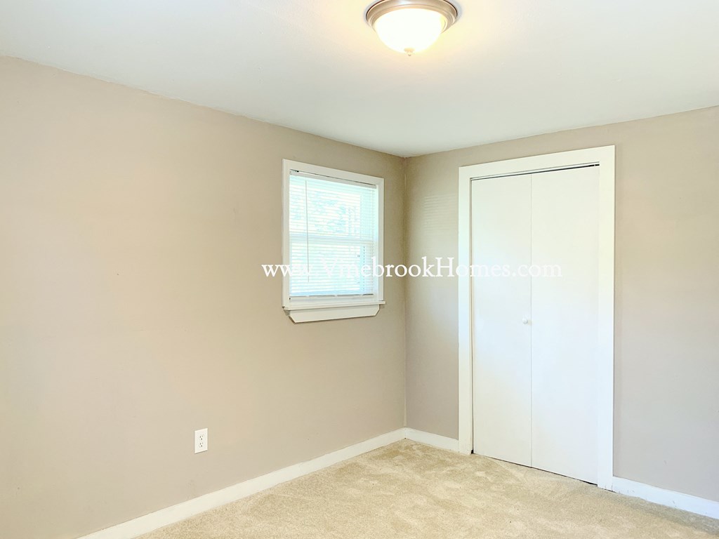 a bedroom with a closet and a window and a white door