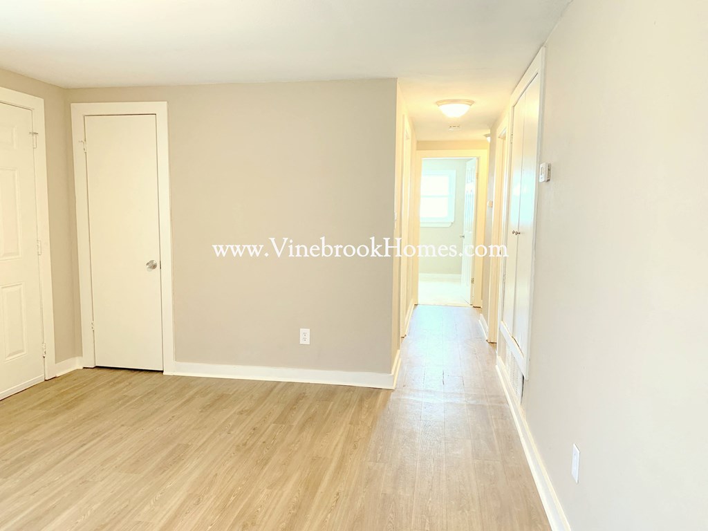 a white bedroom with wood floors and a hallway with white doors