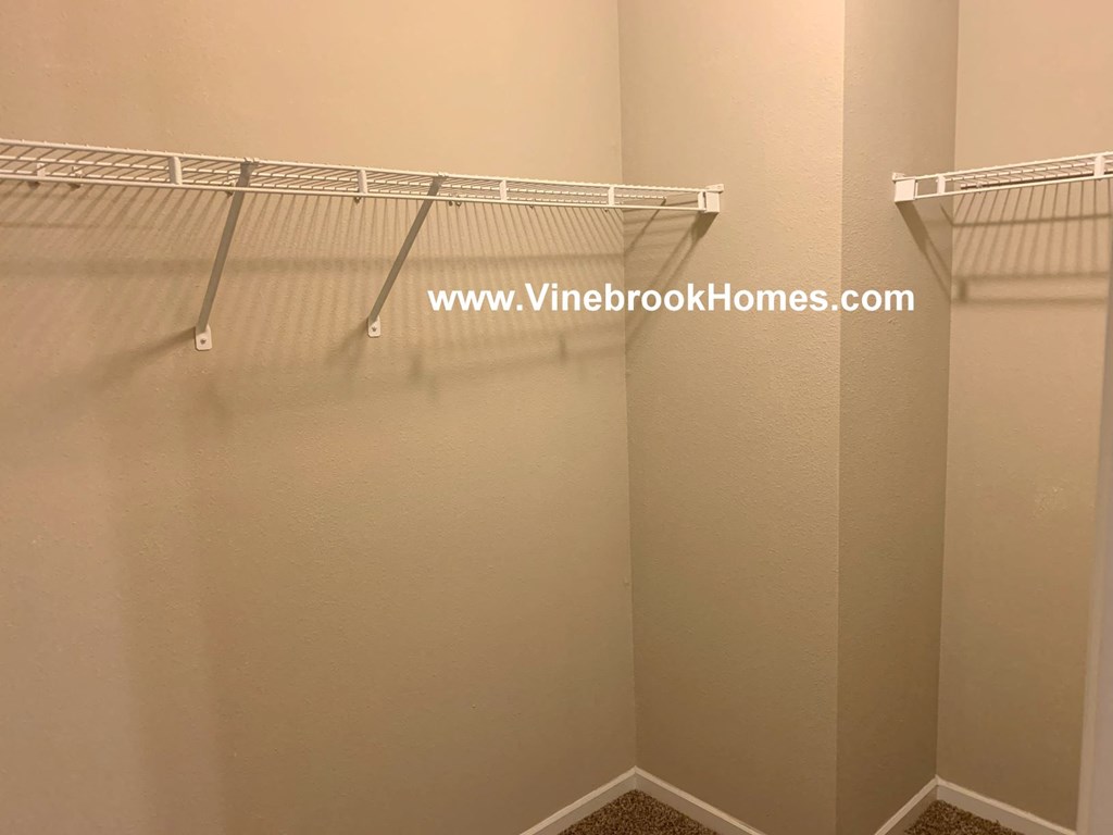 a walk in closet with two hanging racks in a small closet