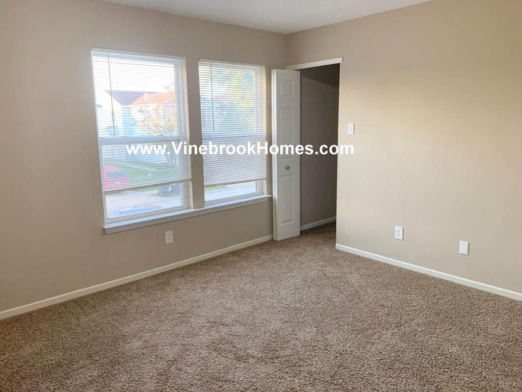 a bedroom with three windows and a carpeted floor