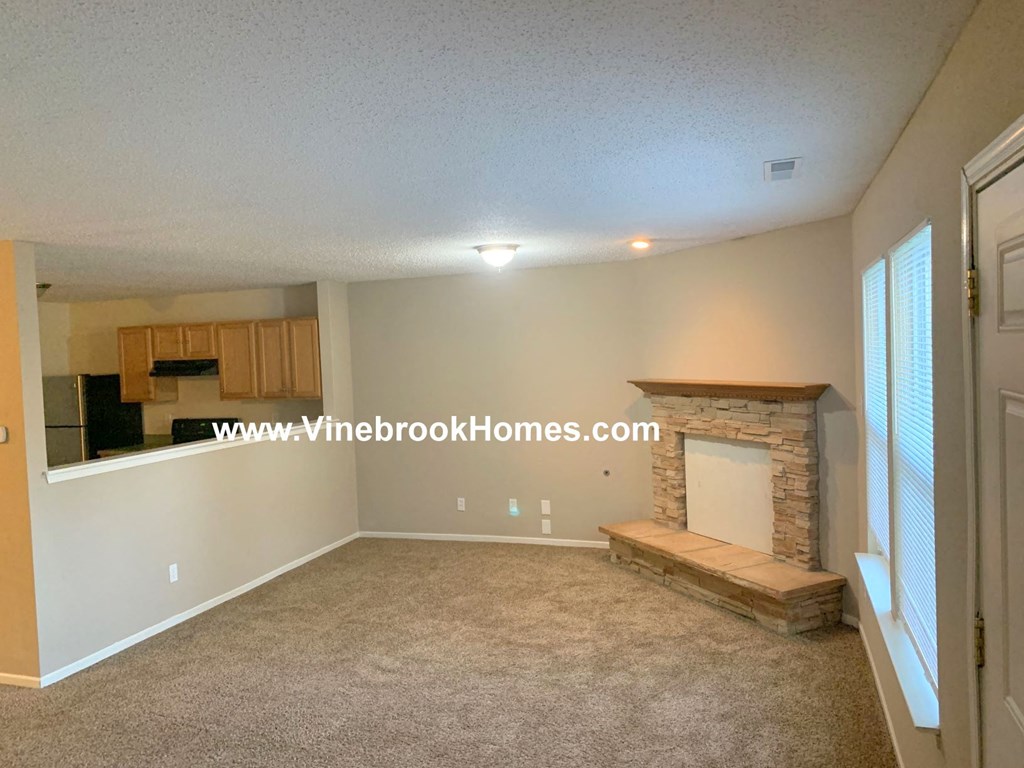 an empty living room with a fireplace and a window