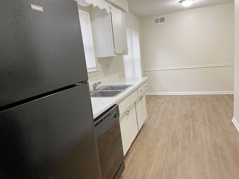 A kitchen with a black fridge and white cabinets.