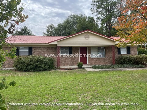 a small brick house with a lawn in front