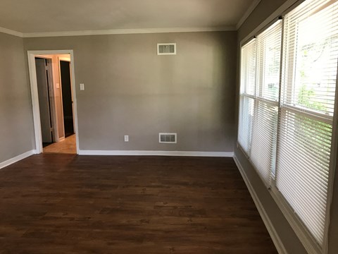 an empty living room with wood flooring and large windows