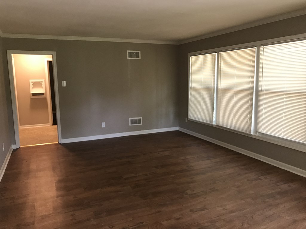 an empty living room with wood floors and large windows