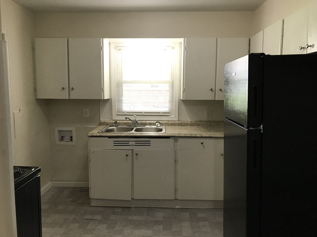 a kitchen with white cabinets and a sink and a refrigerator