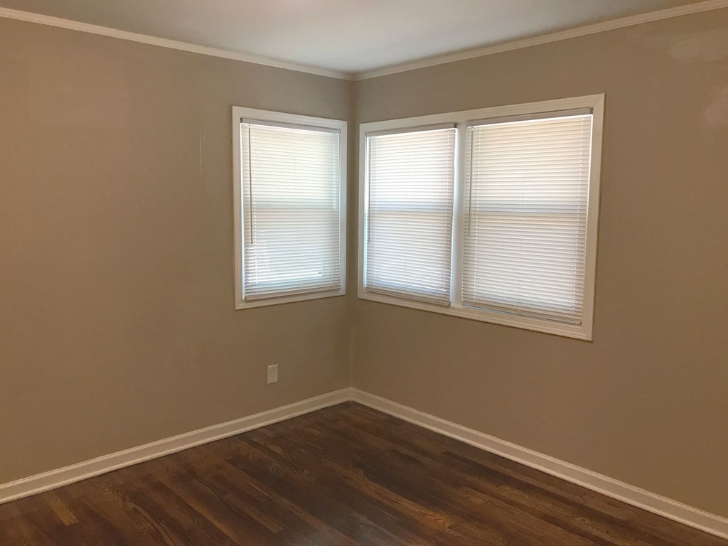 the corner of a room with three windows and a wooden floor