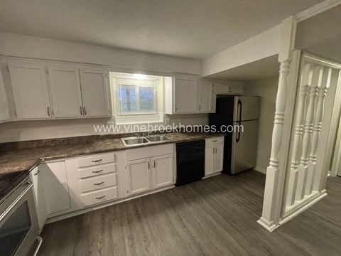 A kitchen with white cabinets and a brown countertop.