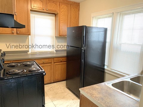 A kitchen with a black refrigerator and a black stove top.