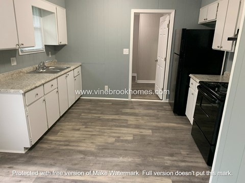 A kitchen with a black refrigerator and white cabinets.