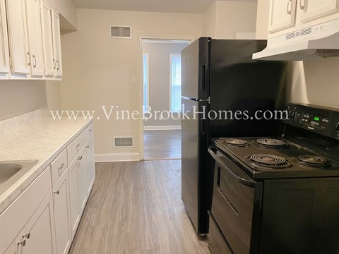 A kitchen with a black refrigerator and white cabinets.