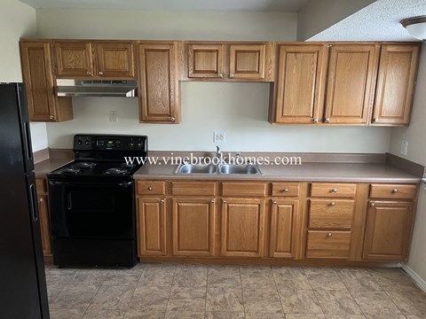 A kitchen with wooden cabinets and black appliances.