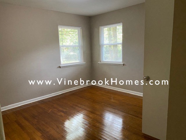 a living room with a hard wood floor and two windows
