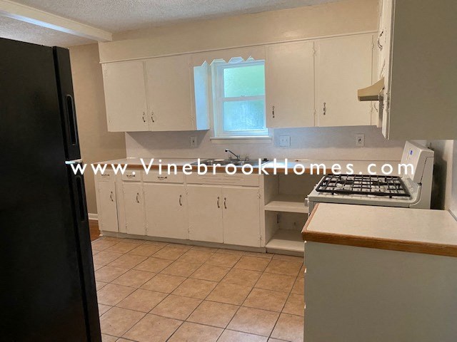 a kitchen with white cabinets and a stove and a window