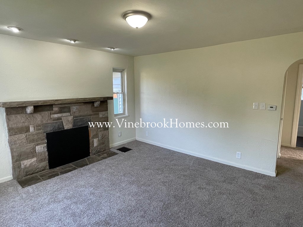a living room with a stone fireplace and a carpeted floor